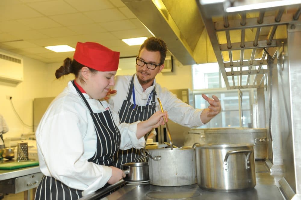 student chefs mixing the pot