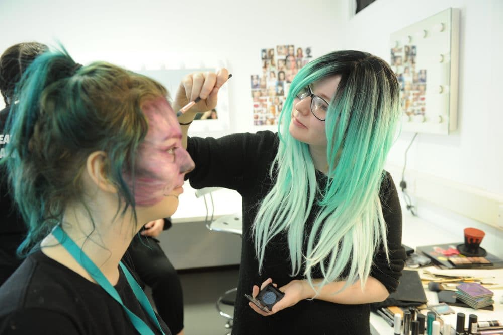 student putting make up on another student