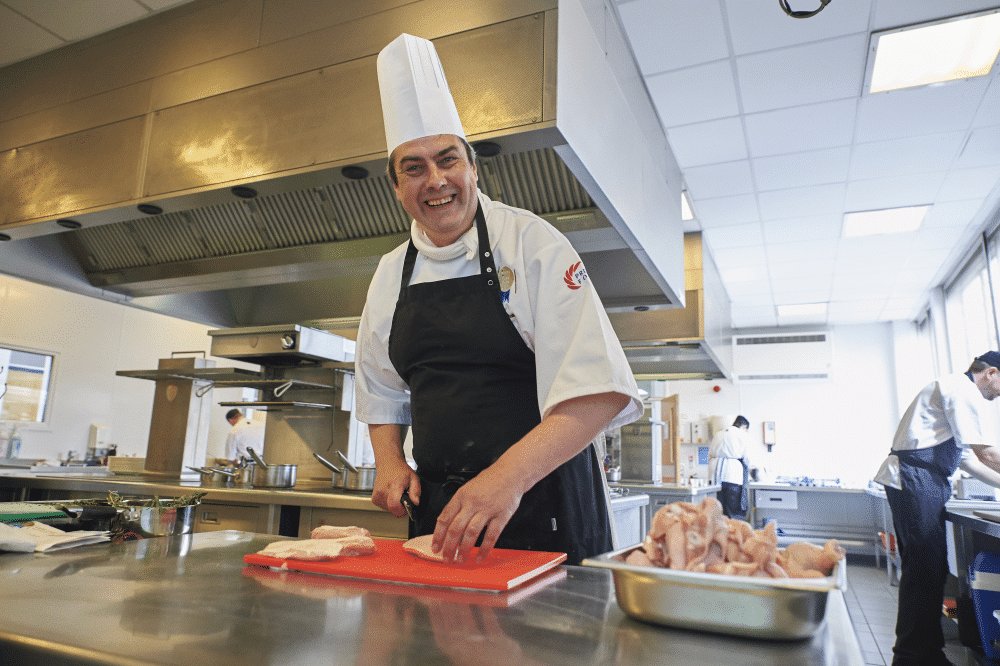 Care home chef cutting chicken