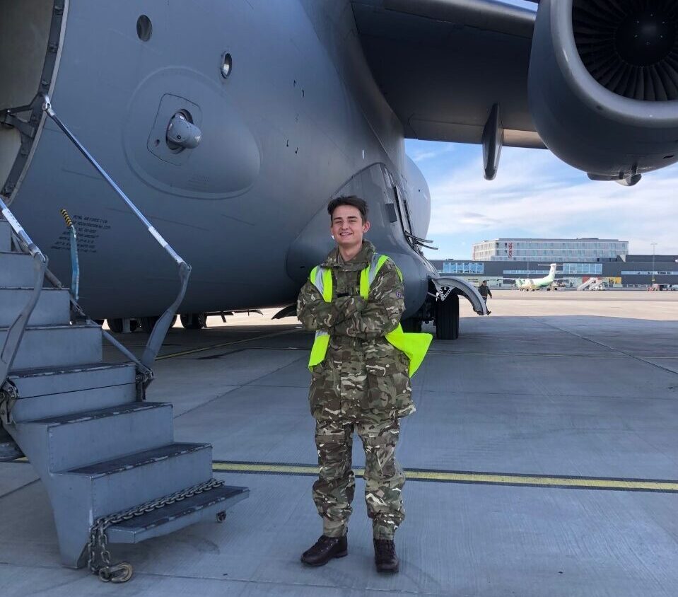Student in RAF uniform standing in front of plane
