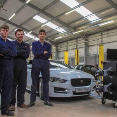 4 students standing by car looking at camera at Stratford-Upon-Avon College