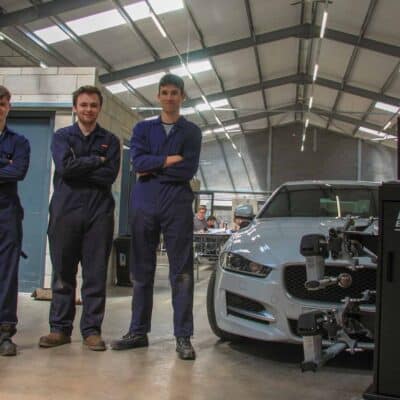 4 students standing next to car with arms crossed