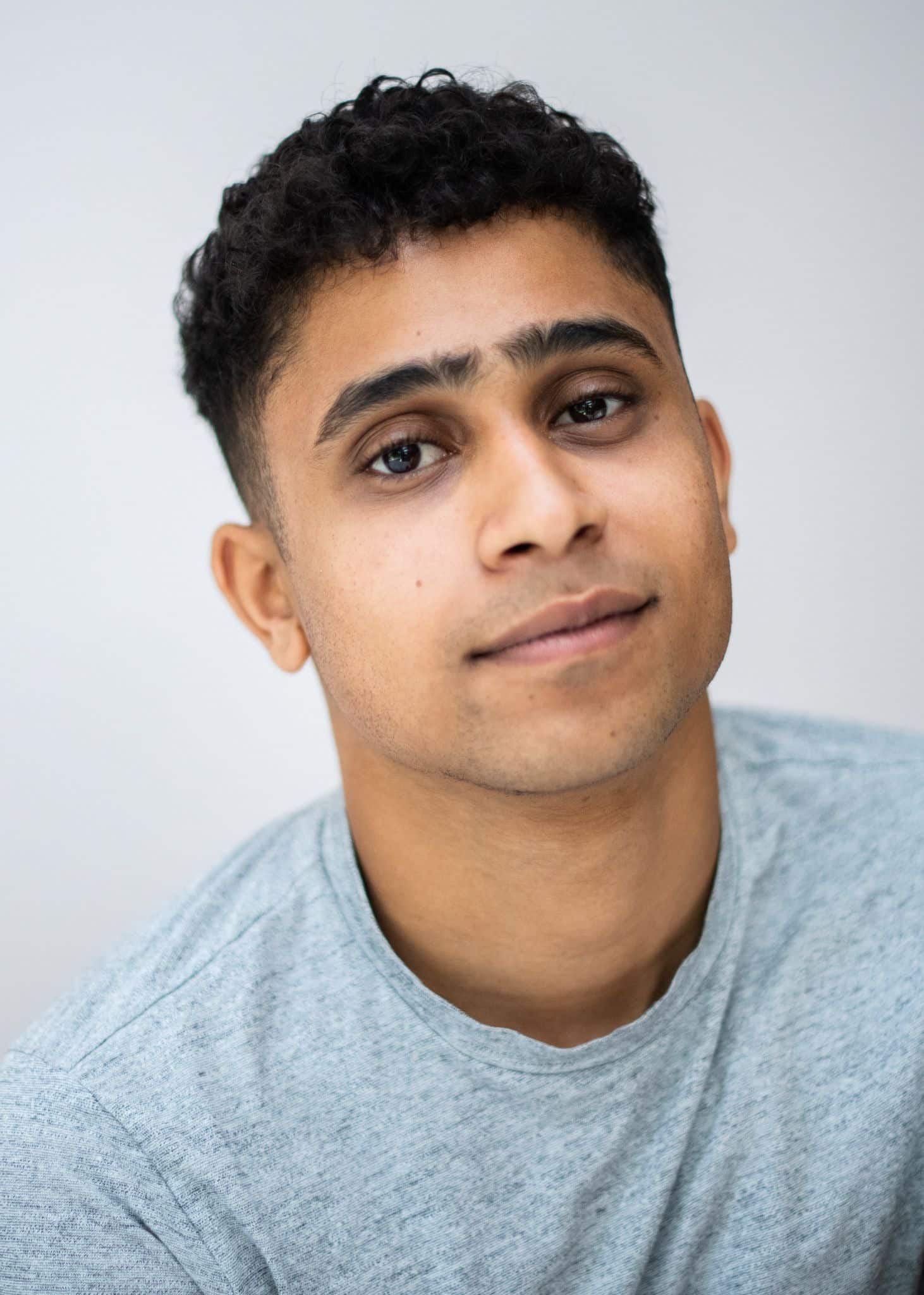 Man in a grey tshirt smiling at a camera
