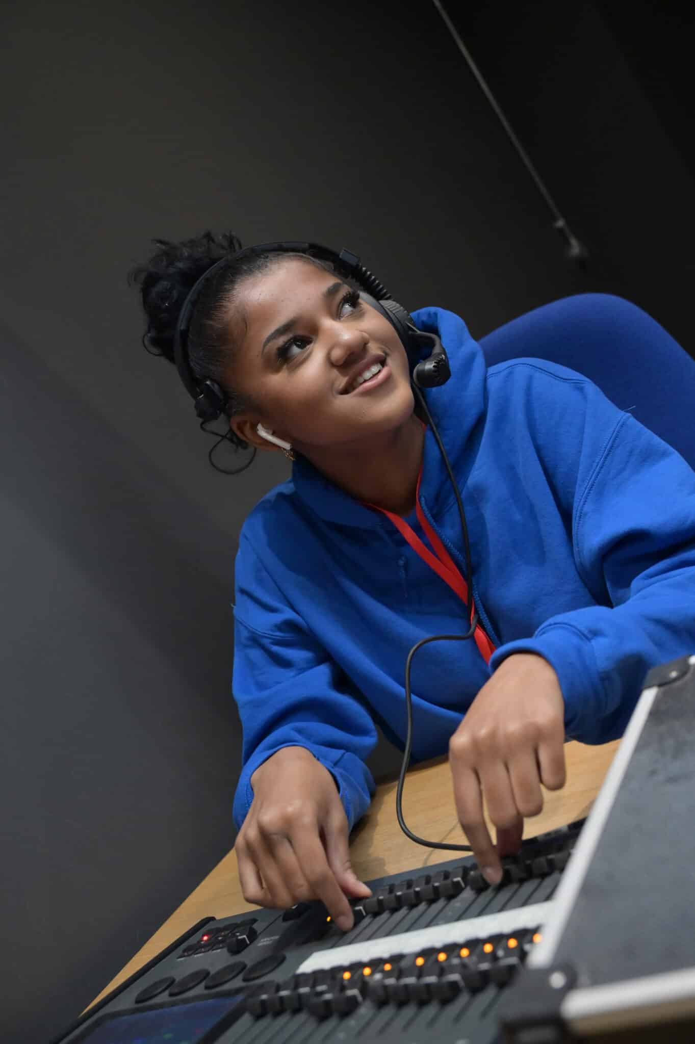 Girl in blue hoodie smiling in a radio studio