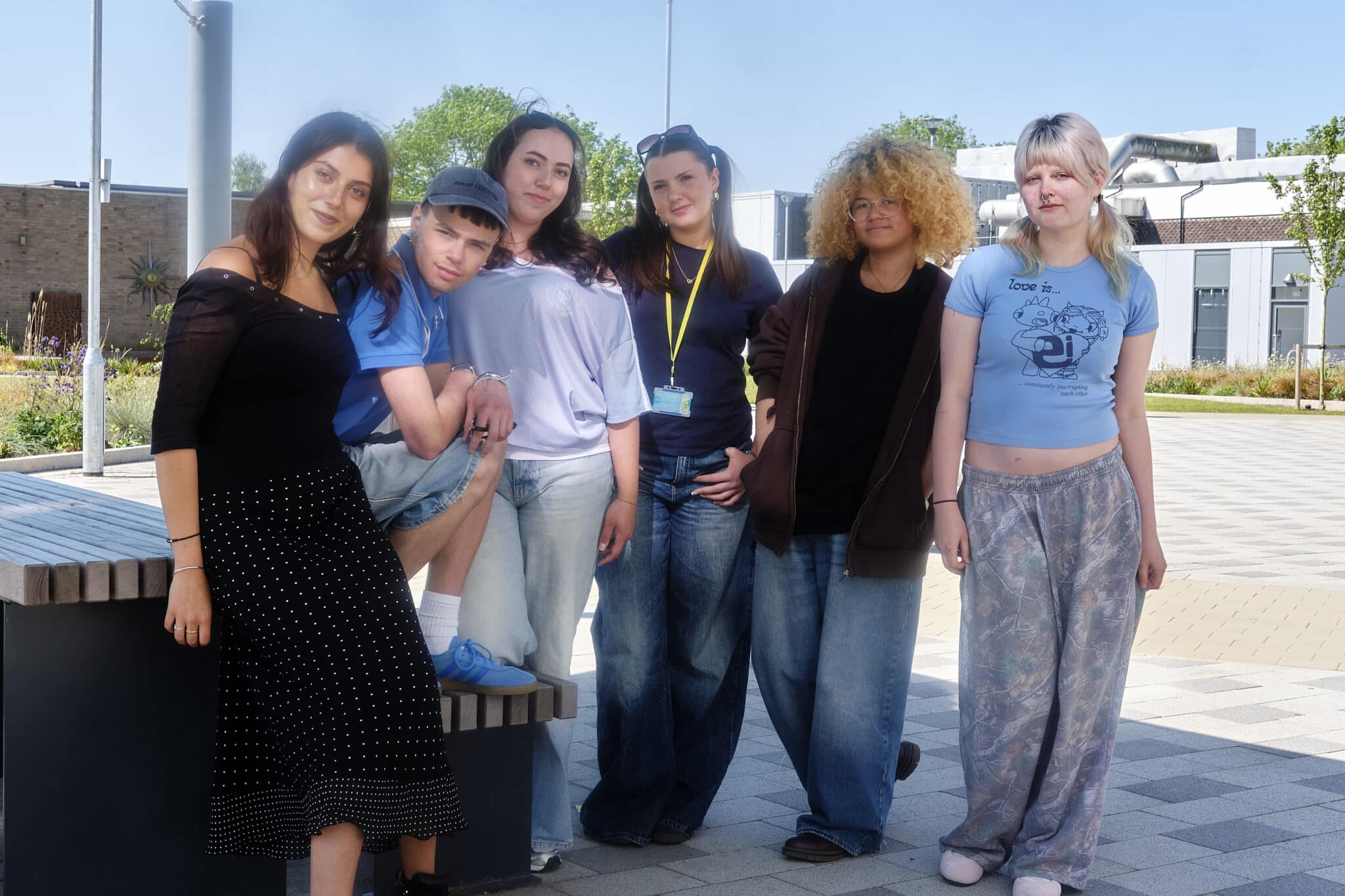 Some students stood by a bench with a blue sky.