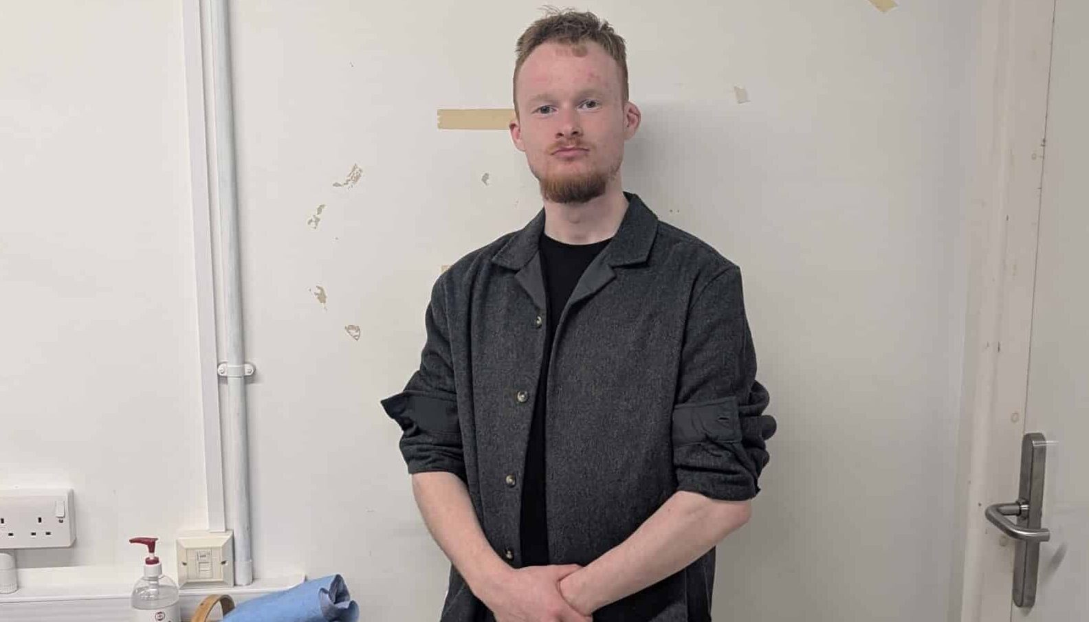Man looking at a camera leaning against the wall