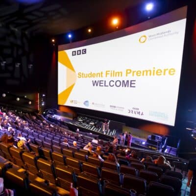 People sat looking at a big screen in a big