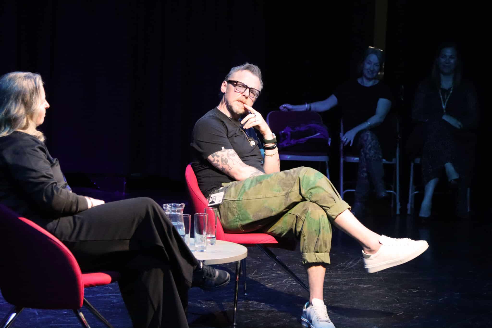 simon pegg sitting on stage thinking