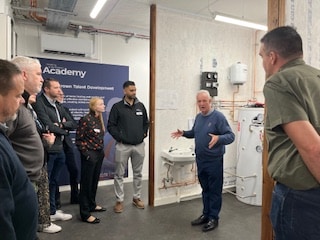 people listening to guest speaker in new heat pump facility