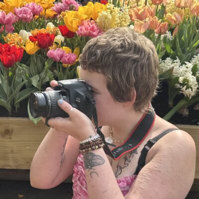 student with a camera infront of tulips