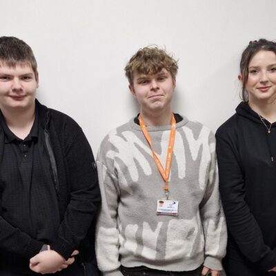 three college students against a white wall