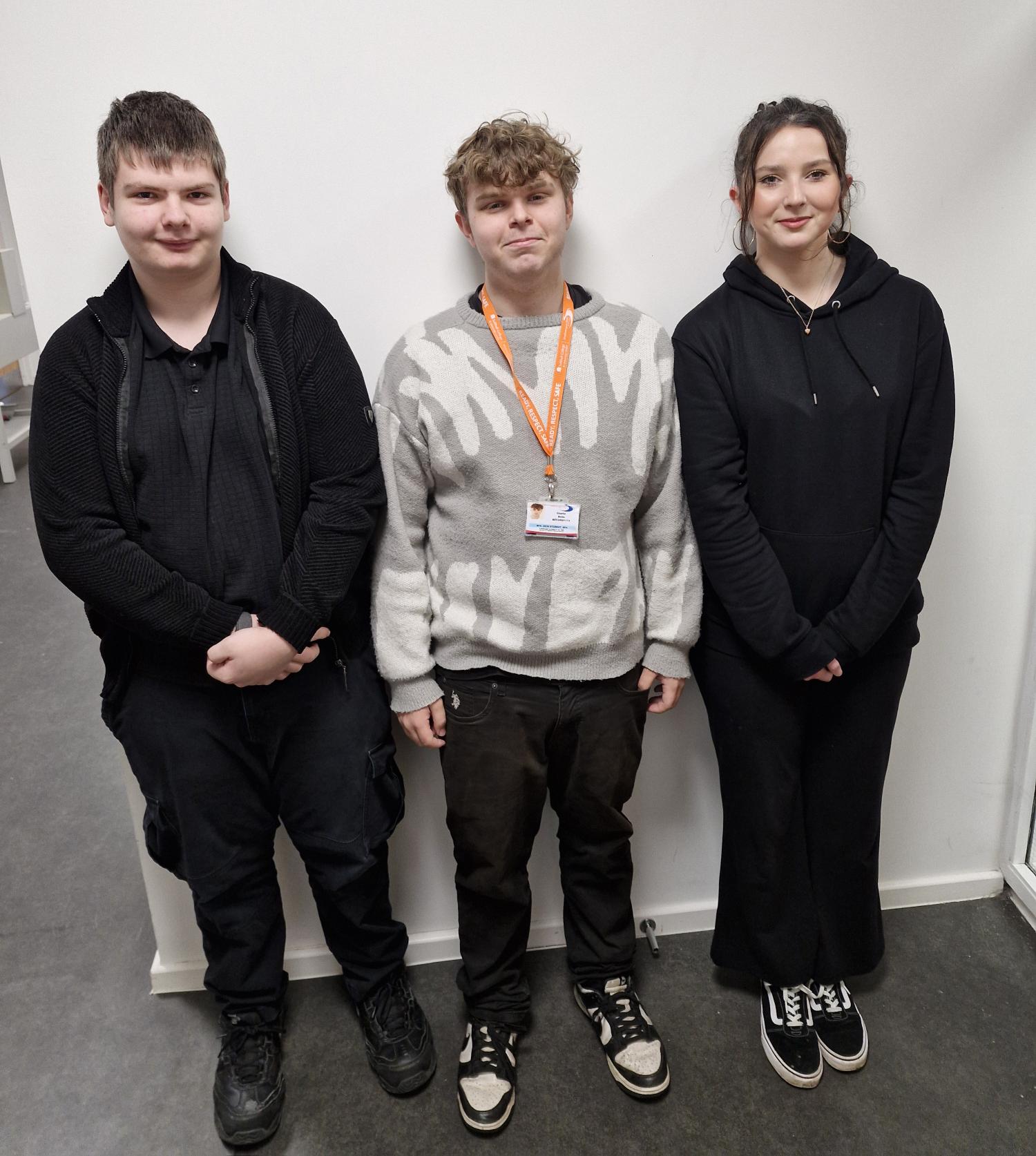 three college students standing against a white wall