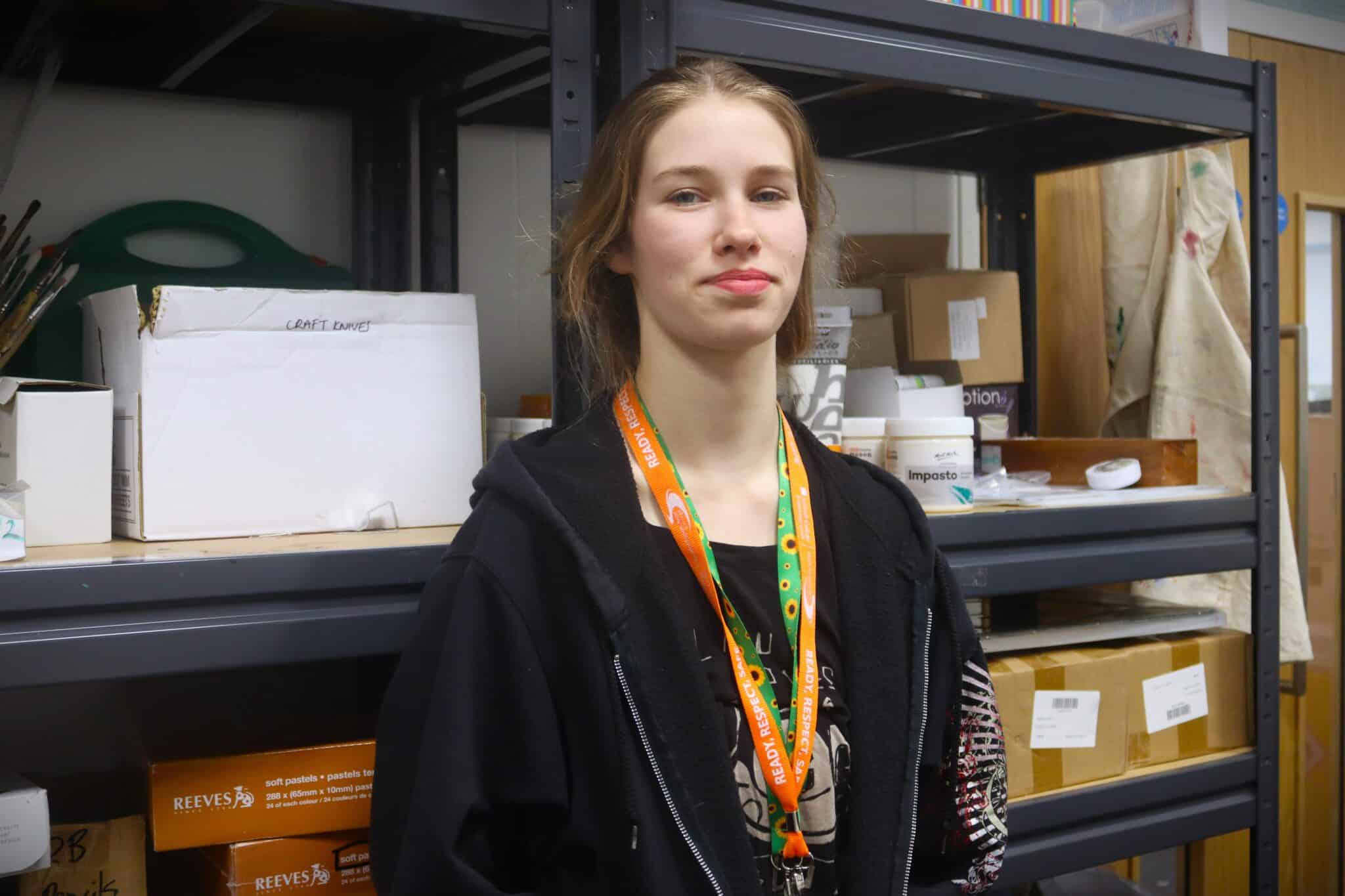 Student standing infront of art supply shelves