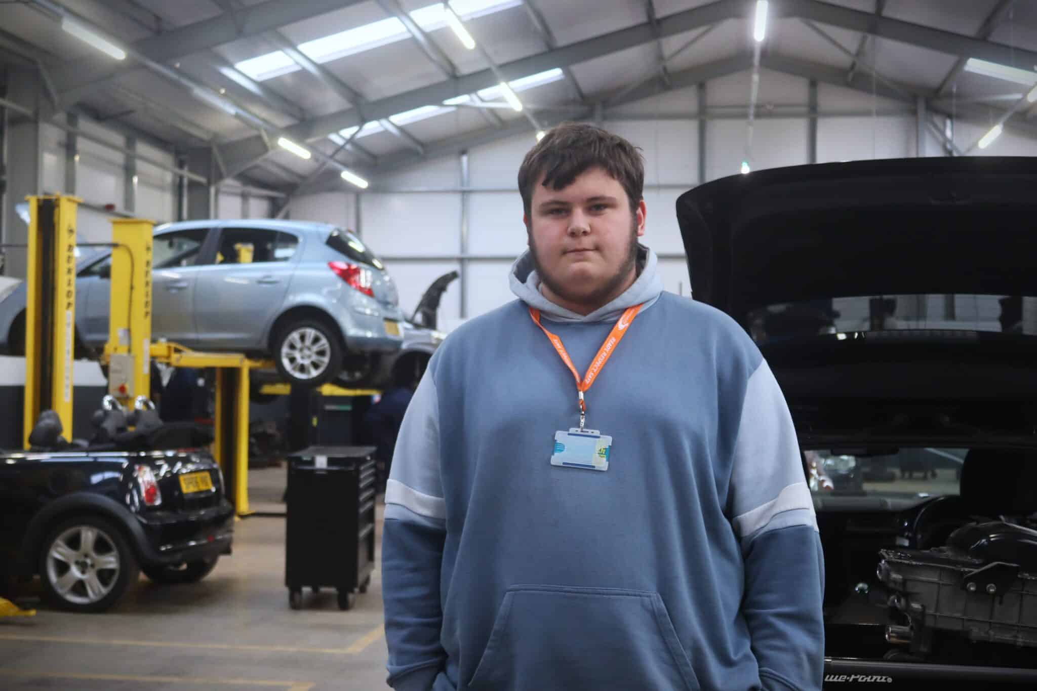 student standing in front of vehicle workshop