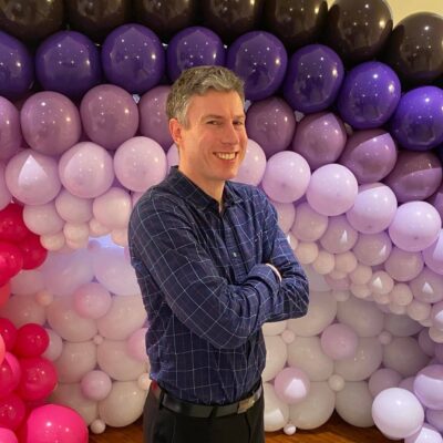 man standing in front of purple ombre balloons