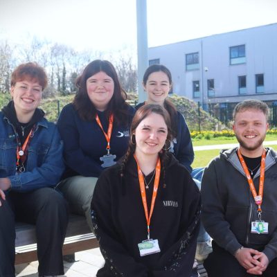 students sat on bench in campus grounds